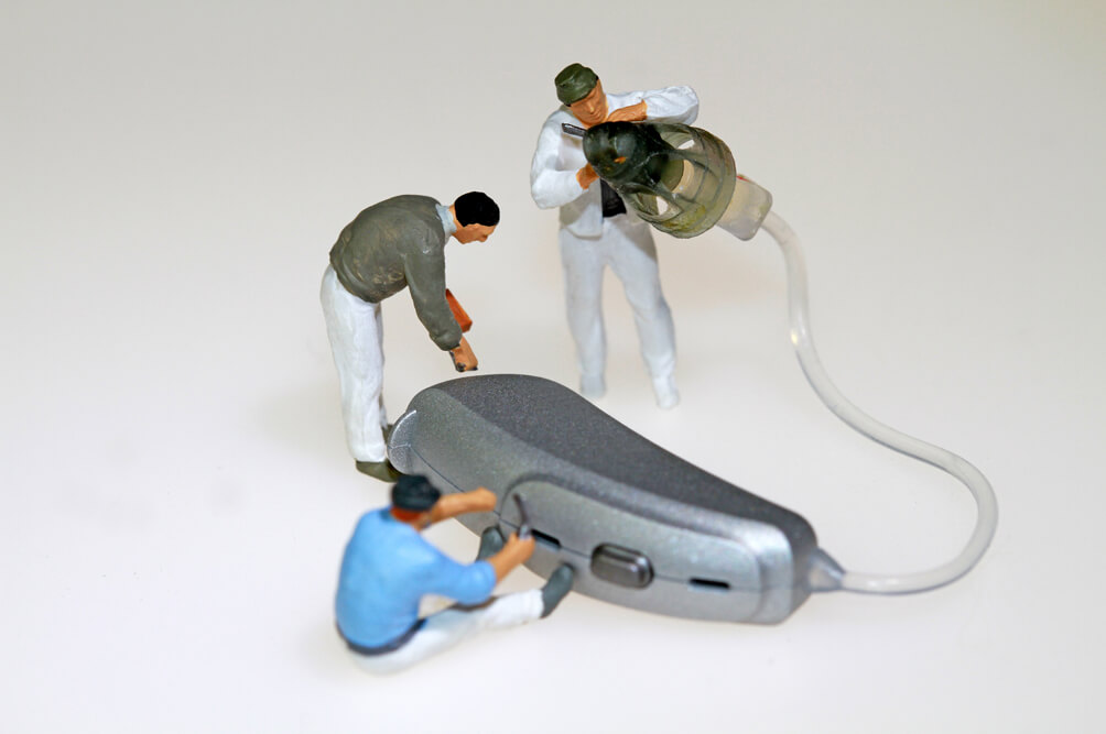 Hörgeräte Service figurines working on hearing aid
